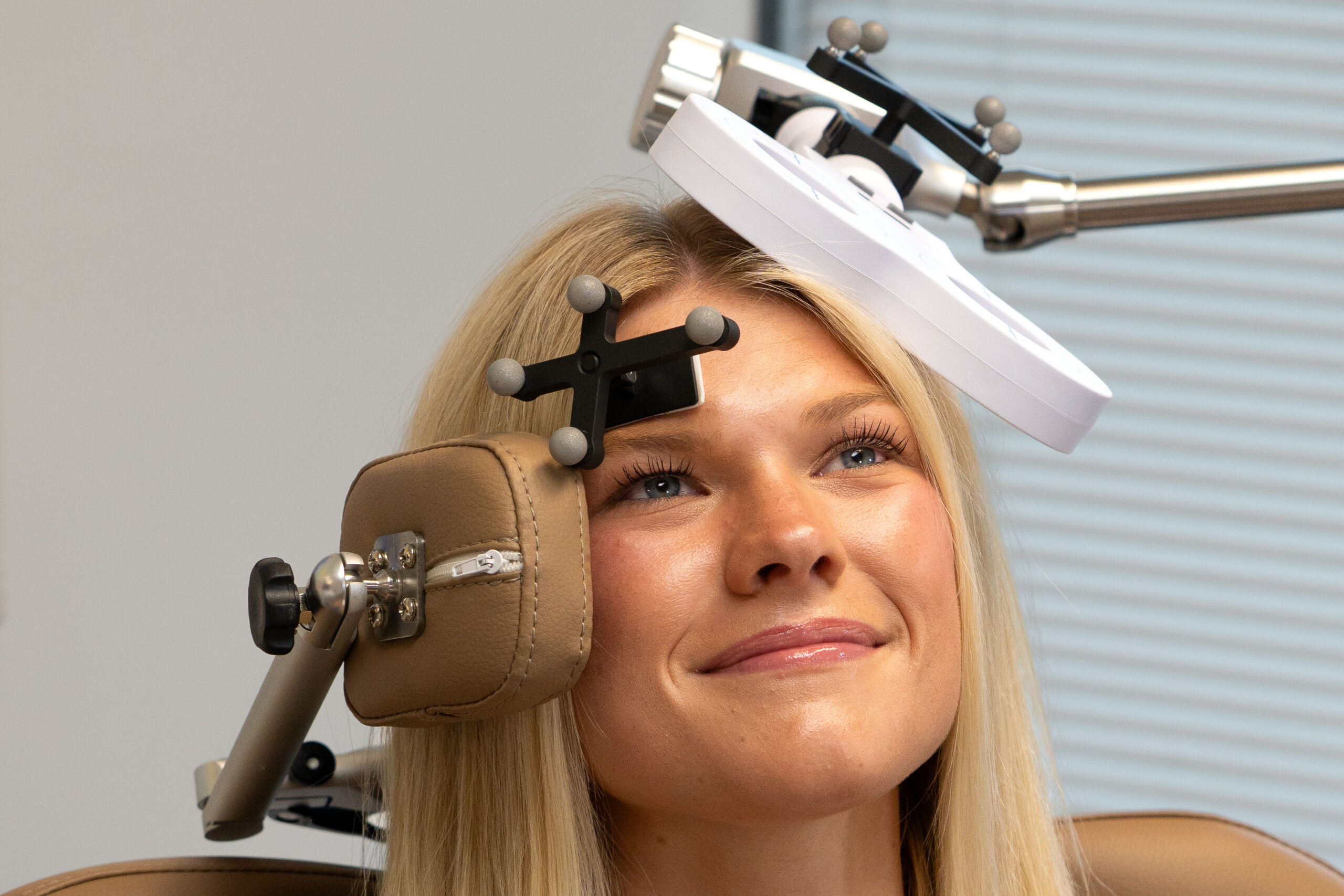 Close-up of the treatment coil and the optical tracking sensor positioned on the patient's head, with reference markers secured before tracking begins.